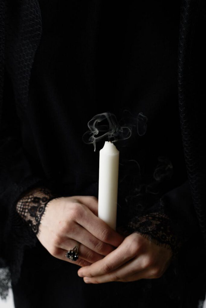 Close-up of hands gently holding an extinguished candle with smoke, symbolizing loss and grief.